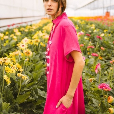 Vestido rosa vivo com manga curta e bolso lateral junto a flores numa estufa