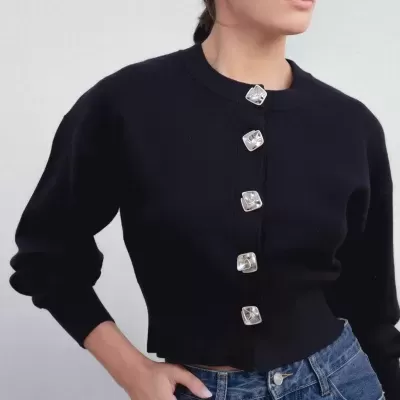 Camisola preta de malha com botões prateados e jeans azul