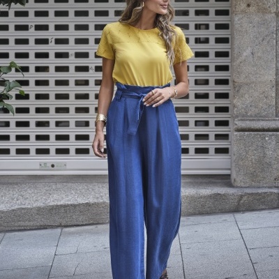 Mulher com blusa amarela e calças largas azuis em cidade