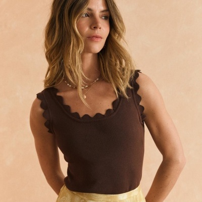 Mulher com camisa castanha e saia amarela com padrão floral