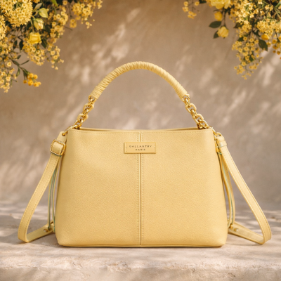 Mala amarela com textura, alça superior e alças laterais ajustáveis, em fundo com flores amarelas