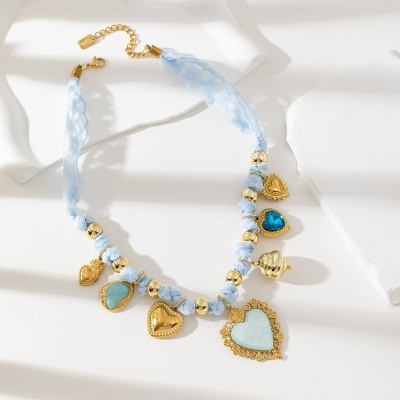 Colar azul claro com contas e pendentes dourados em fundo branco.