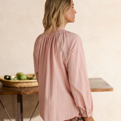 Blusa rosa claro feminina com detalhes em renda nas costas e punhos, combinada com calças florais rosas
