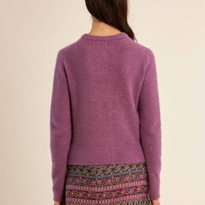 Mulher vista de costas com suéter roxo e saia estampada colorida