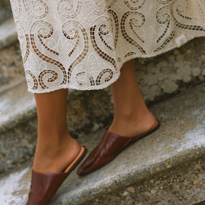 Sapatos mule castanhos em pele com vestido branco bordado em renda