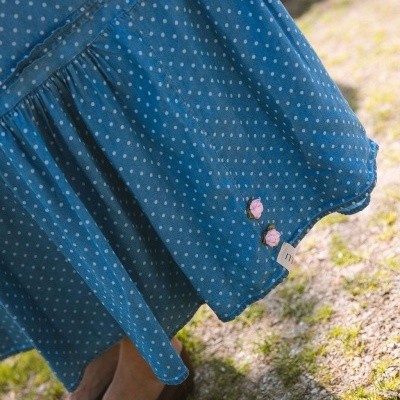 Saia azul com bolinhas brancas e botões florais rosas na bainha