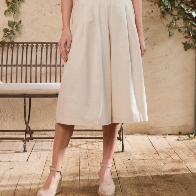 Calças culottes bege com cinto castanho e sapatos espadrille em madeira