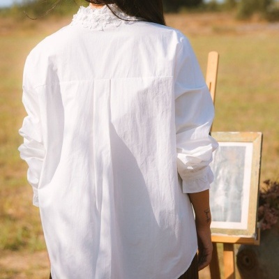 Camisa branca de algodão com renda no colarinho vista de costas ao ar livre