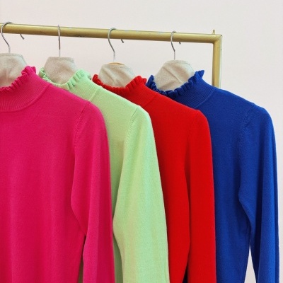 Quatro camisolas coloridas com gola alta e folhos penduradas