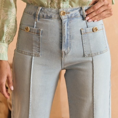 Calças de ganga azul claro com bolsos botões castanhos e camisa verde transparente