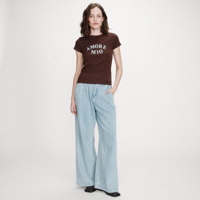 Mulher a usar t-shirt castanha com texto e calças largas azuis