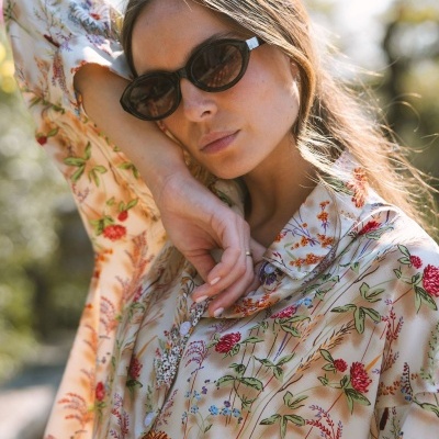 Camisa feminina floral bege com botões brancos e óculos escuros negros