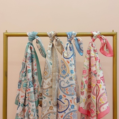 Lenços de cetim com padrões florais e cachemira pendurados numa barra