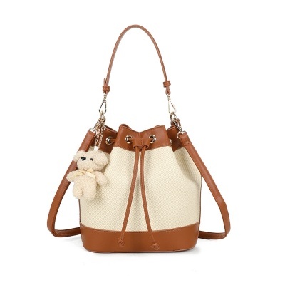 Mala saco bege com detalhes em pele castanha e ursinho pendurado