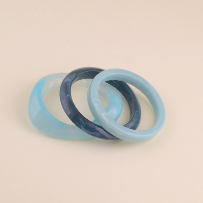 Três pulseiras lisas em tons azul sobre fundo bege