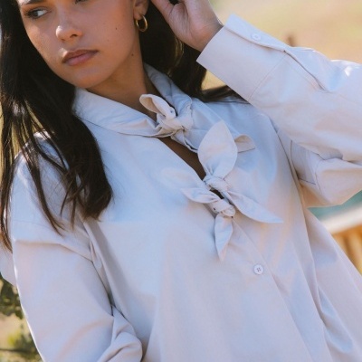 Blusa branca com nós decorativos em mulher ao ar livre