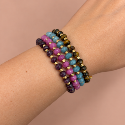 Pulseiras coloridas de contas facetadas com detalhes dourados num pulso