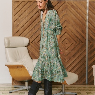 Vestido verde com padrão paisley e botas pretas em ambiente interior
