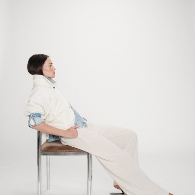 Mulher sentada com casaco branco e camisa de ganga