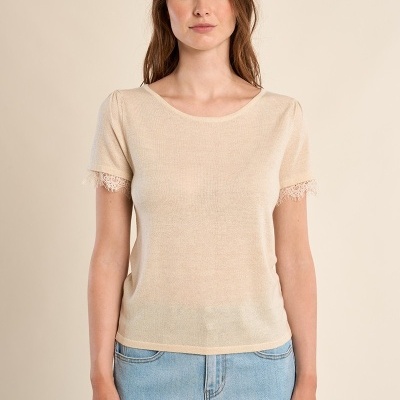 Mulher com t-shirt bege de malha fina com renda nas mangas e jeans claros