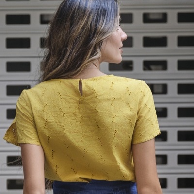 Blusa amarela com padrão bordado e saia azul com cinto largo