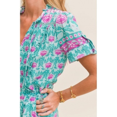 Blusa feminina floral verde e rosa com mangas curtas e acessórios dourados.