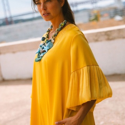 Vestido amarelo com mangas almofadadas e colar azul e verde