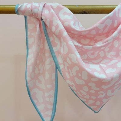 Lenço rosa com padrão branco e borda azul pendurado
