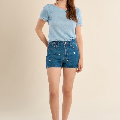 Mulher a vestir t-shirt azul clara com renda e calções de ganga bordados