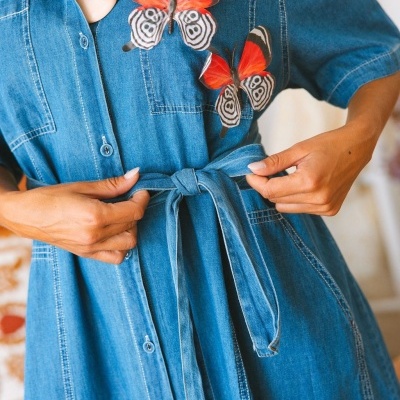 Vestido de ganga azul com cinto e borboletas decorativas no bolso