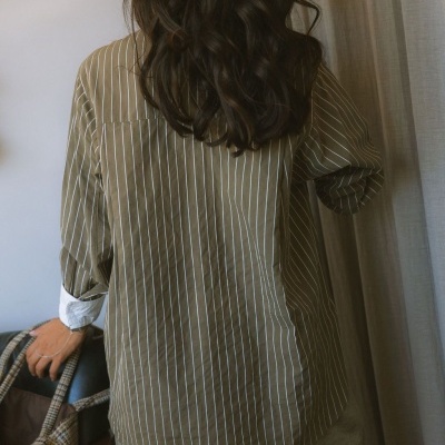 Camisa riscada castanha vista de costas com mala xadrez