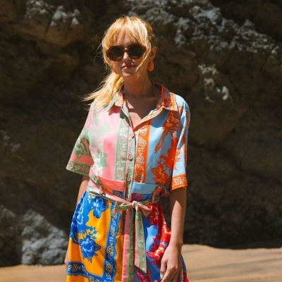 Vestido curto colorido com padrão floral e de pássaros usado por mulher com óculos escuros
