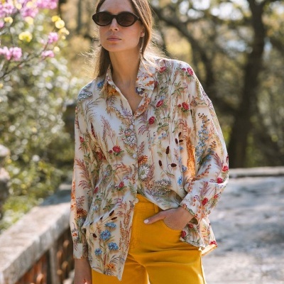Mulher com camisa floral e calças amarelas ao ar livre