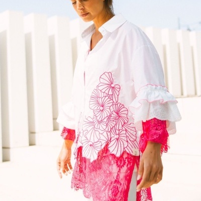 Camisa branca com bordados florais rosa e renda rosa em modelo feminino.