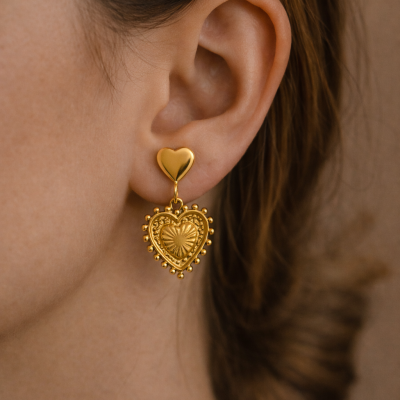Brinco dourado em forma de coração na orelha de uma pessoa