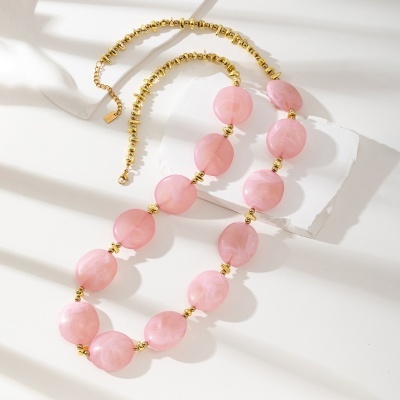 Colar rosa com contas grandes e pequenas contas douradas sobre fundo branco