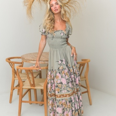 Vestido comprido verde com flores e mangas bufantes ao lado de mesa de madeira