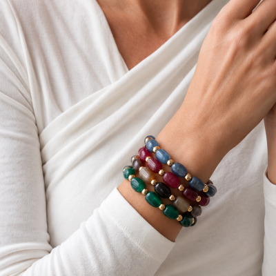 Pulseiras coloridas em contas e esferas douradas no pulso