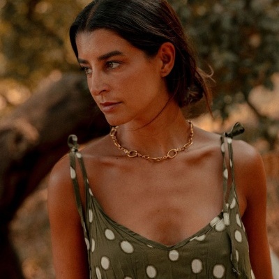 Vestido verde com bolas brancas e colar dourado em ambiente exterior