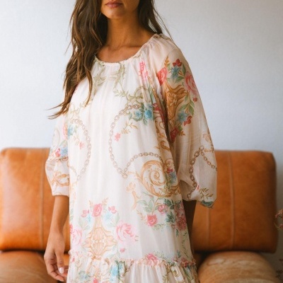 Vestido feminino floral com padrão em tons pastel e detalhes dourados