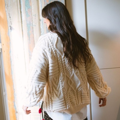 Camisola de malha bege com padrão trançado vista de costas.