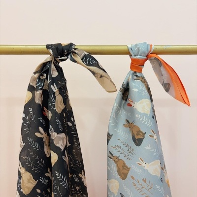 Duas echarpes de seda com padrão de coelhos penduradas num varão dourado