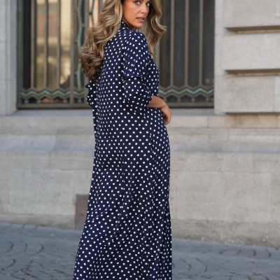 Vestido comprido azul escuro com bolinhas brancas usado por mulher de costas