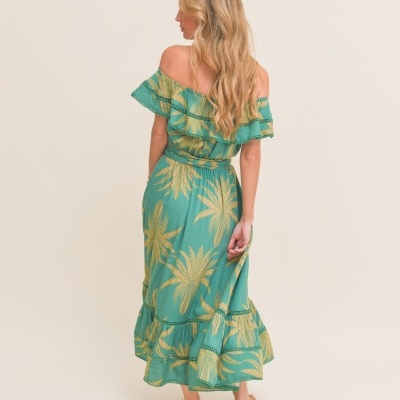 Vestido verde com padrão dourado e folhos usado por mulher vista de costas