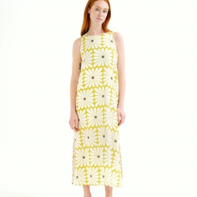 Vestido midi amarelo com flores brancas e sandálias brancas.