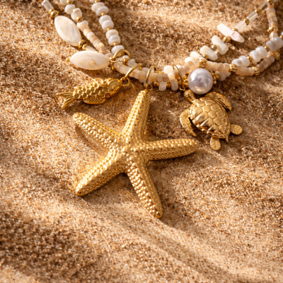 Colar com contas brancas e douradas e pendentes marinhos em areia