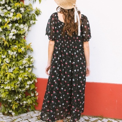 Vestido floral preto com manga bufante e chapéu de palha visto de costas