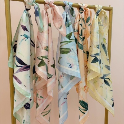 Seis lenços florais coloridos pendurados num cabide dourado