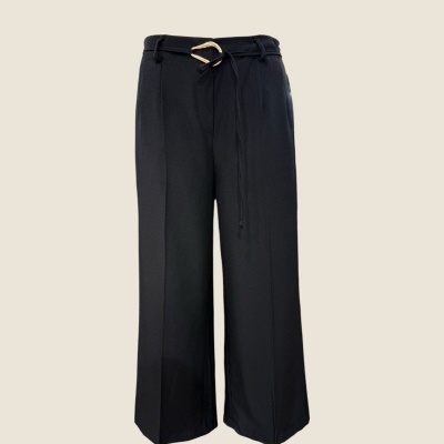 Calças pretas largas com cinto preto e fivela dourada sobre fundo bege