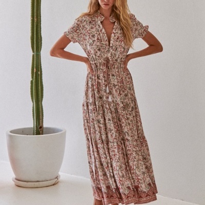 Vestido feminino longo floral com mangas curtas e cordão na cintura, modelo descalça e cacto em vaso branco ao lado